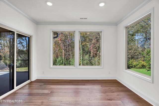 unfurnished dining area with ornamental molding, a healthy amount of sunlight, and hardwood / wood-style flooring