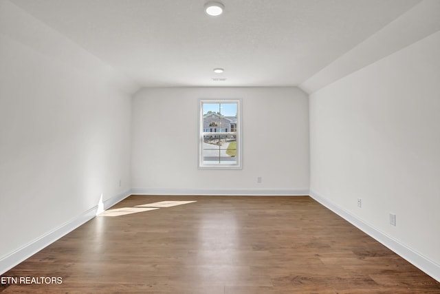 unfurnished room with lofted ceiling and dark wood-type flooring