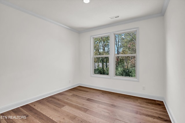 empty room with ornamental molding and light hardwood / wood-style flooring