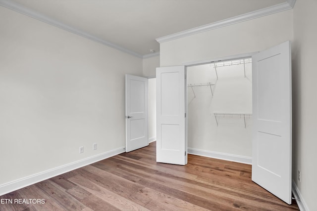 unfurnished bedroom with a closet, crown molding, and hardwood / wood-style flooring