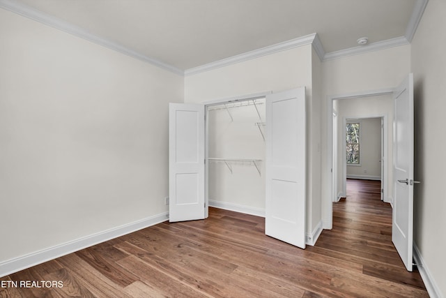 unfurnished bedroom with a closet, crown molding, and hardwood / wood-style floors