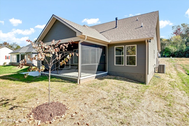 rear view of property featuring central air condition unit and a lawn