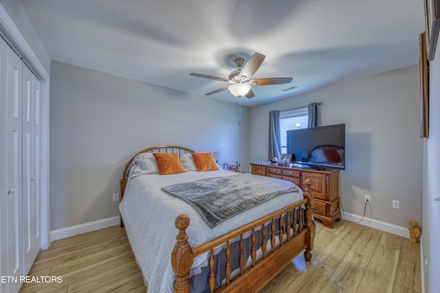 bedroom with light hardwood / wood-style flooring, a textured ceiling, a closet, and ceiling fan