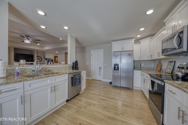 kitchen with appliances with stainless steel finishes, white cabinetry, sink, and light wood-type flooring