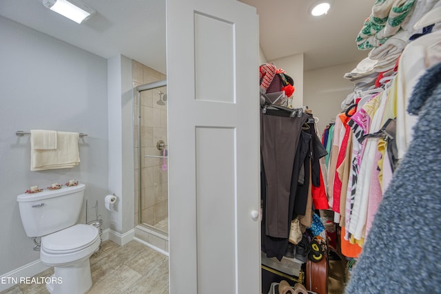 bathroom featuring a shower with door, hardwood / wood-style floors, and toilet