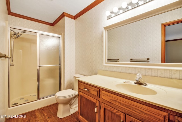 bathroom with toilet, wood-type flooring, a shower with door, ornamental molding, and vanity