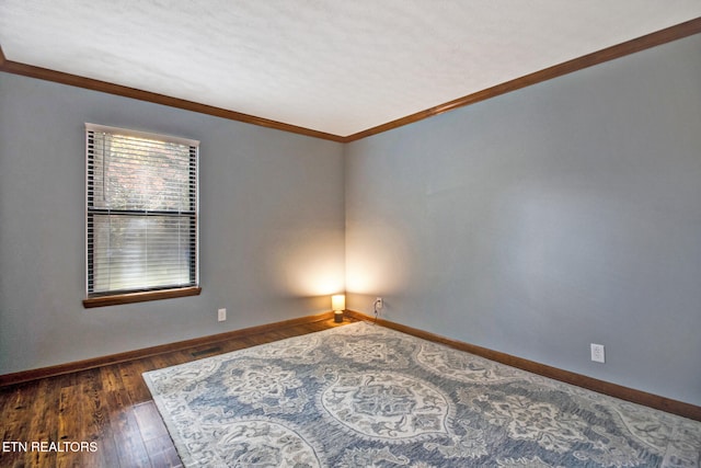 spare room featuring ornamental molding and dark wood-type flooring