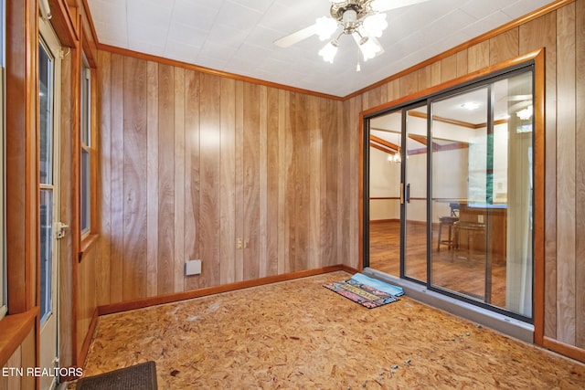 spare room featuring ceiling fan, crown molding, and wooden walls