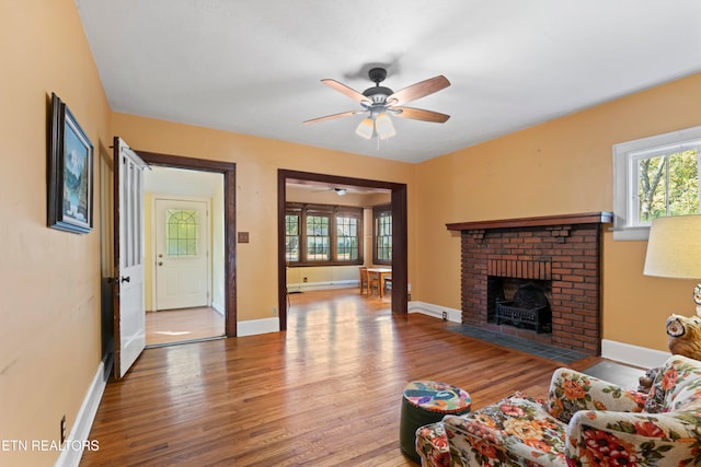 living room with hardwood / wood-style floors, a brick fireplace, and ceiling fan