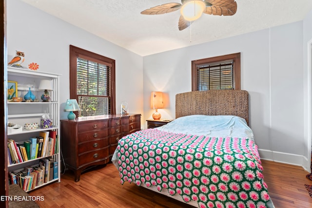 bedroom with a textured ceiling, hardwood / wood-style flooring, and ceiling fan