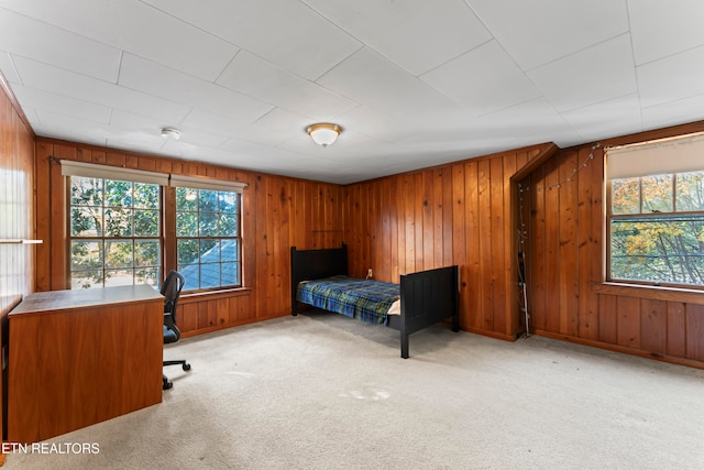 bedroom featuring light carpet and wood walls