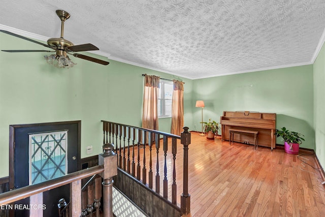 stairway featuring ornamental molding, a textured ceiling, hardwood / wood-style flooring, and ceiling fan