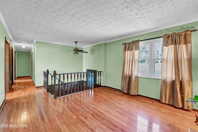 unfurnished room featuring crown molding, wood-type flooring, a textured ceiling, and ceiling fan