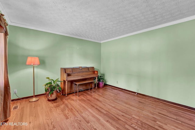 misc room with a textured ceiling, light hardwood / wood-style flooring, and ornamental molding