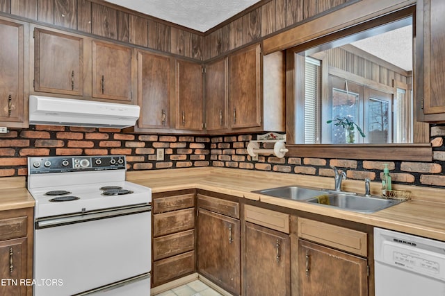 kitchen featuring decorative backsplash, a textured ceiling, butcher block counters, sink, and white appliances