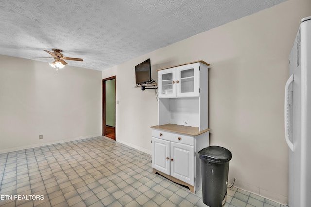 interior space with white cabinetry, ceiling fan, and a textured ceiling