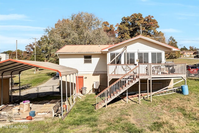 rear view of property with a sunroom, a lawn, and a carport