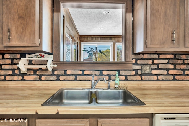 kitchen with washer / dryer, sink, backsplash, a textured ceiling, and wooden counters