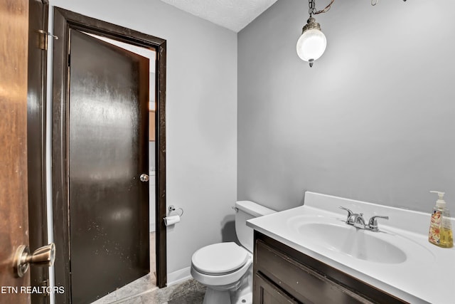 bathroom featuring toilet, a textured ceiling, and vanity