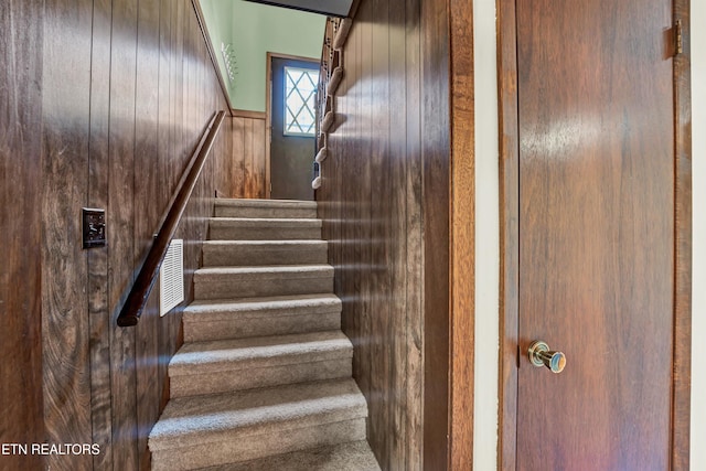 stairway featuring wooden walls