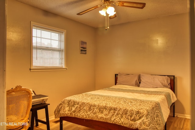 bedroom with ceiling fan, hardwood / wood-style flooring, and a textured ceiling