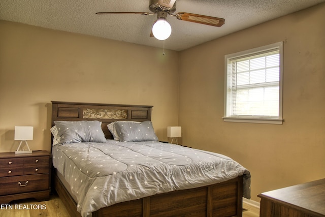 bedroom with a textured ceiling, light wood-type flooring, and ceiling fan