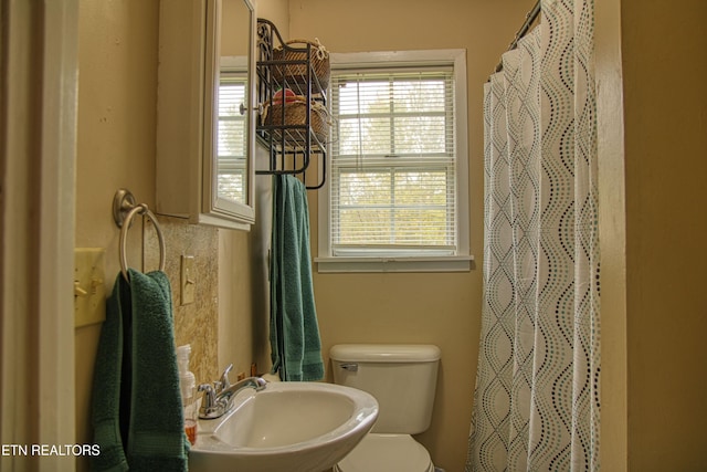 bathroom with toilet, walk in shower, and sink