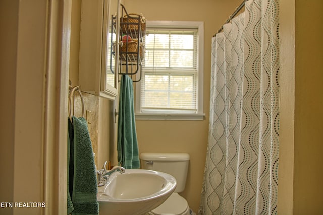 bathroom with toilet, sink, and a shower with curtain