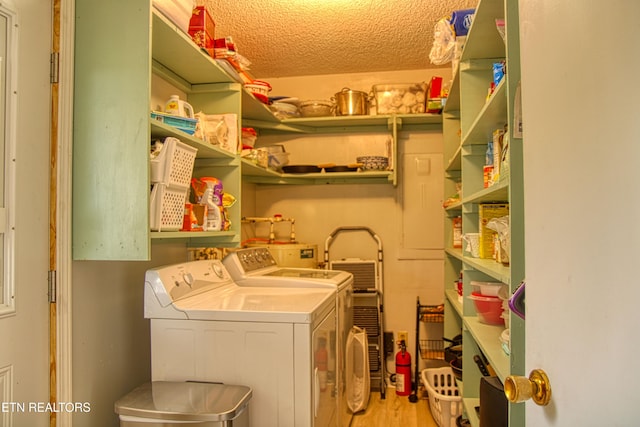 laundry room featuring washing machine and dryer, a textured ceiling, and light hardwood / wood-style floors