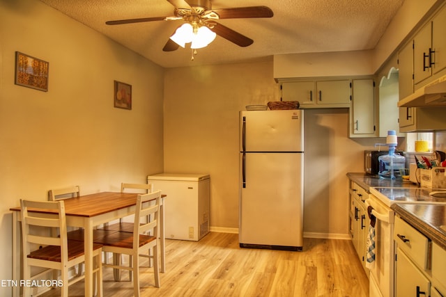 kitchen featuring refrigerator, range, a textured ceiling, light hardwood / wood-style flooring, and white refrigerator