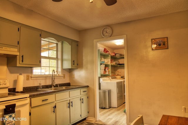 kitchen featuring sink, white range, washing machine and clothes dryer, light hardwood / wood-style flooring, and exhaust hood