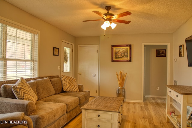 living room featuring light hardwood / wood-style flooring, a textured ceiling, and ceiling fan