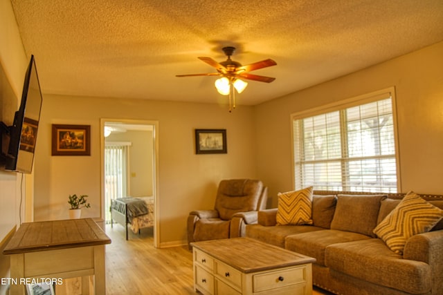 living room with light hardwood / wood-style floors, a textured ceiling, and ceiling fan