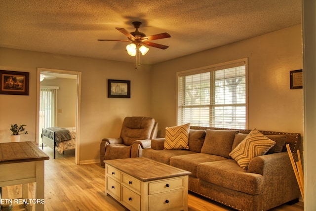 living room featuring a textured ceiling, light hardwood / wood-style floors, and ceiling fan