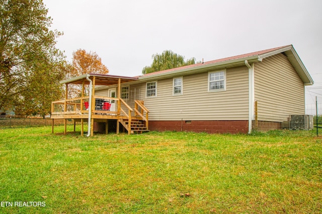 rear view of property with a deck, a lawn, and cooling unit