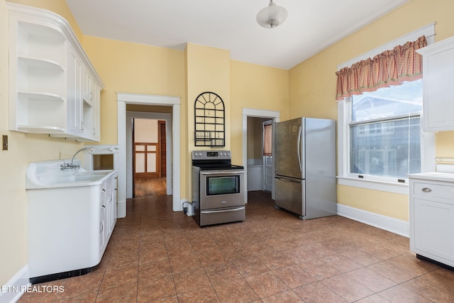 kitchen featuring appliances with stainless steel finishes, white cabinets, sink, and dark tile patterned floors