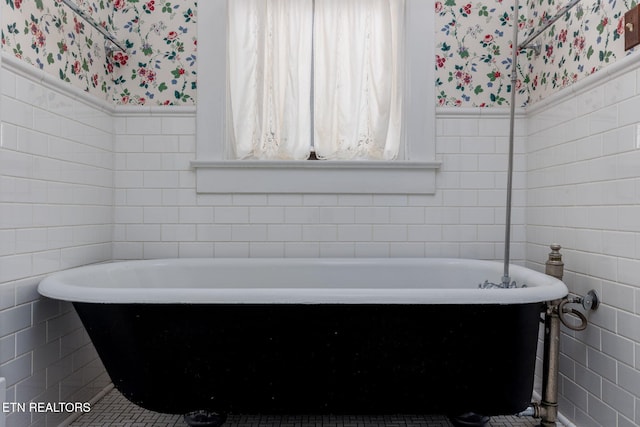 bathroom with a tub to relax in and tile walls