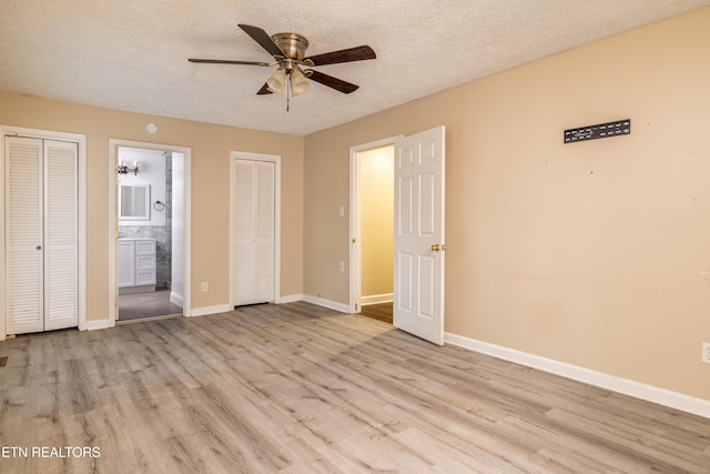 unfurnished bedroom featuring light hardwood / wood-style floors, two closets, and connected bathroom