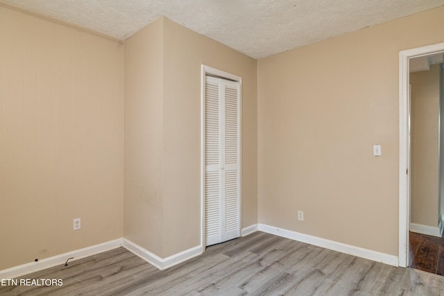 unfurnished bedroom with a closet, a textured ceiling, and light hardwood / wood-style flooring