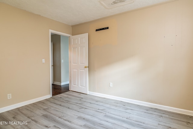 unfurnished room featuring a textured ceiling and light hardwood / wood-style floors