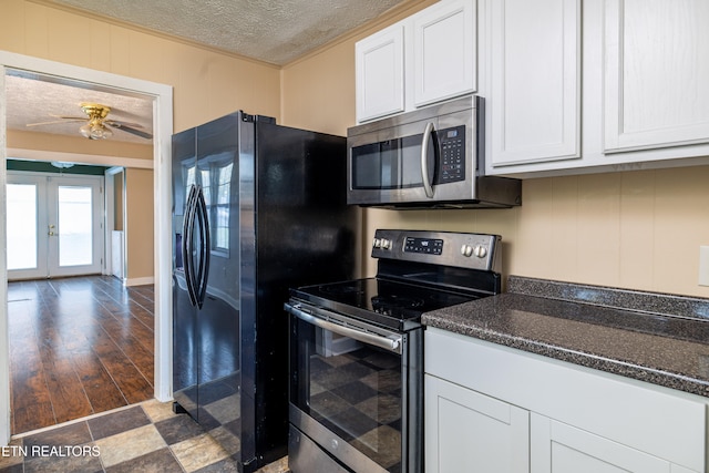 kitchen with a textured ceiling, white cabinetry, stainless steel appliances, dark wood-type flooring, and ornamental molding