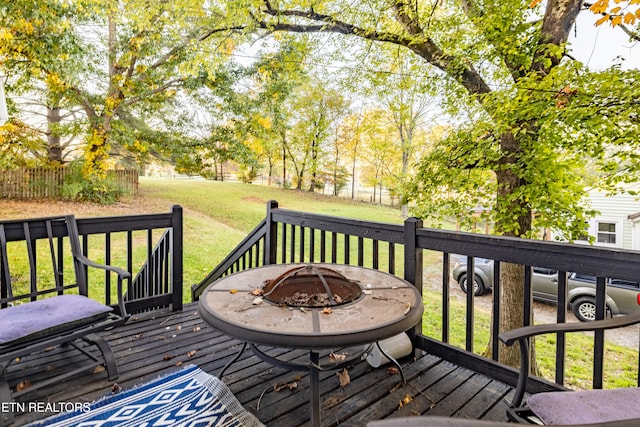 wooden deck featuring an outdoor fire pit and a lawn