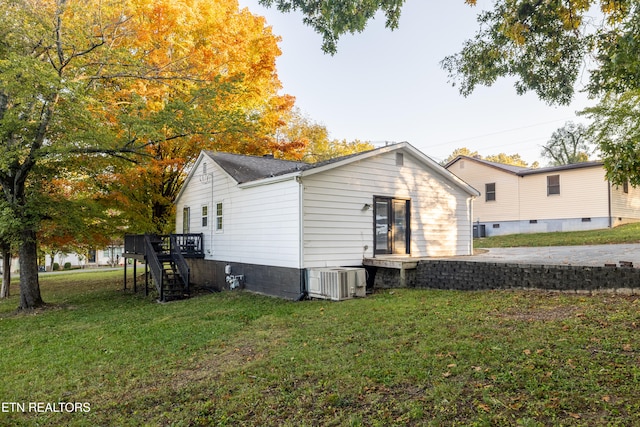 view of side of home with central air condition unit and a lawn