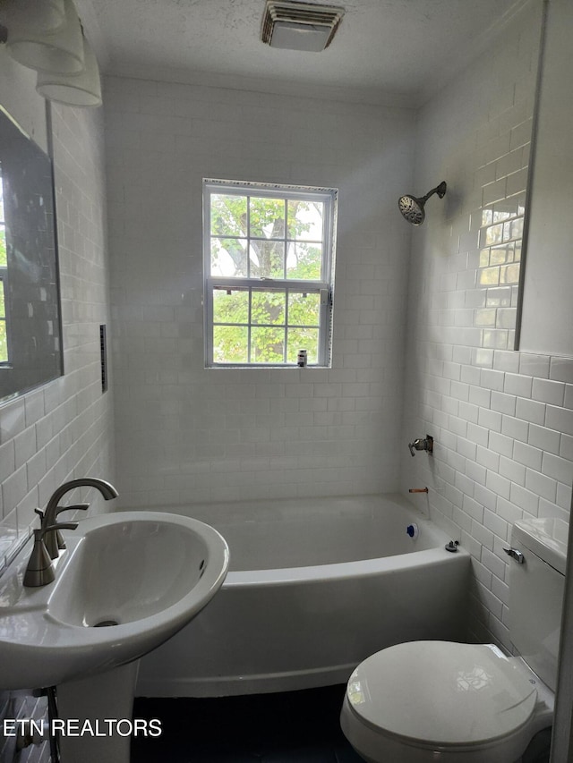 full bathroom with toilet, tiled shower / bath, and tile walls