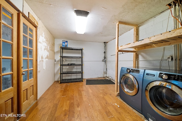 clothes washing area featuring washing machine and clothes dryer and light hardwood / wood-style flooring