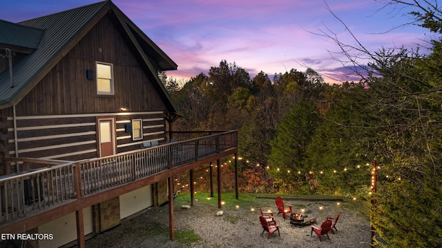 back house at dusk featuring a deck and a fire pit