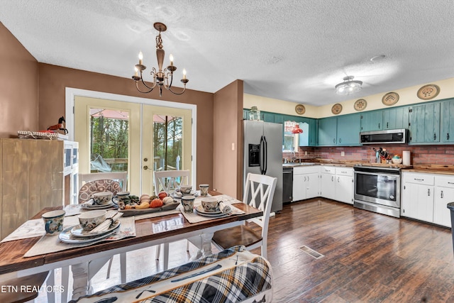 kitchen featuring appliances with stainless steel finishes, french doors, backsplash, pendant lighting, and dark wood-type flooring