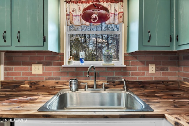 kitchen with sink, decorative backsplash, green cabinets, and wood counters