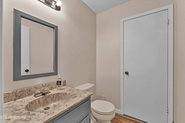 bathroom with vanity, toilet, a textured ceiling, and hardwood / wood-style floors