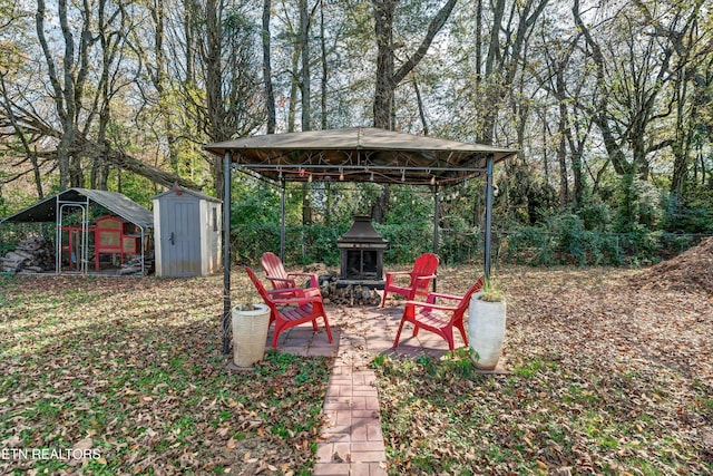 view of yard with a patio, a gazebo, a storage unit, and an outdoor fireplace